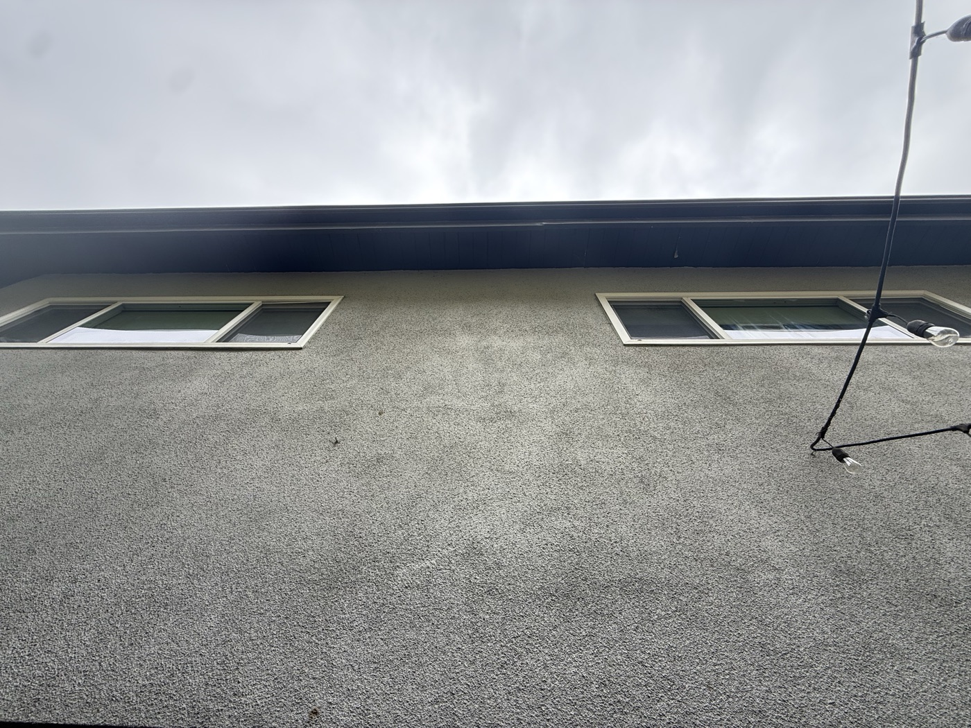 Second-story exterior wall with two windows where the rig will mount under the eave